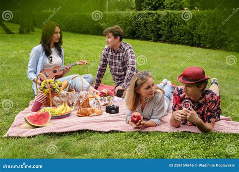 Four Friends Having Fun At Picnic In Public Park Stock Photo Image Of