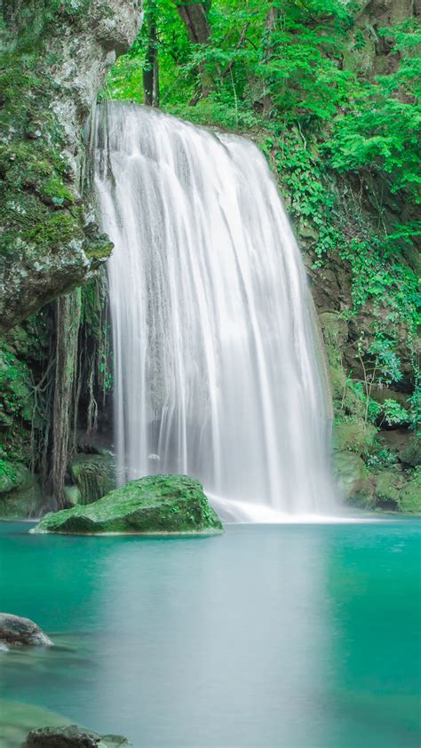 Beautiful Waterfall From Rock Pouring On Lake Between Green Trees