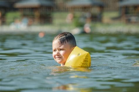 Niño pequeño niño nadando en el lago con apoyo de ayudas de brazos