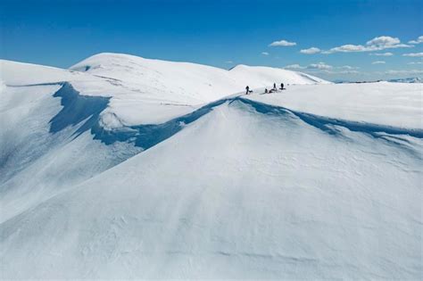 Un Grupo De Personas Se Paran En La Cima De Una Monta A Nevada Con Un