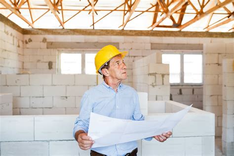 Leitender Architekt oder Bauingenieur auf der Baustelle mit Blaupausen