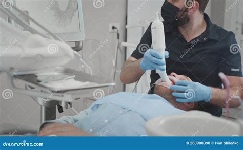 A Male Orthodontist Doctor Scans A Man S Teeth And Jaw In The Clinic S