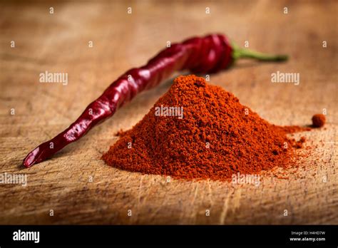 Red Hot Paprika Powder Heap And One Dried Chilli On Wooden Background Stock Photo Alamy