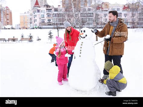 Happy family making snowman in park on winter vacation Stock Photo - Alamy