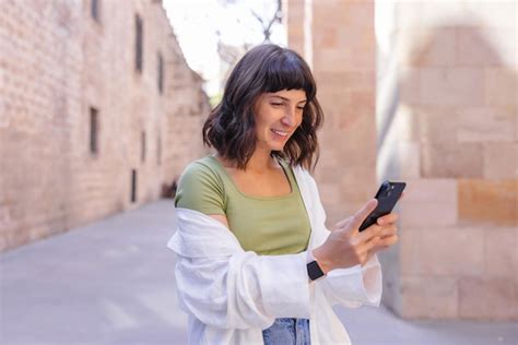 Mulher jovem e atraente sorrindo ao telefone na cidade Foto Grátis