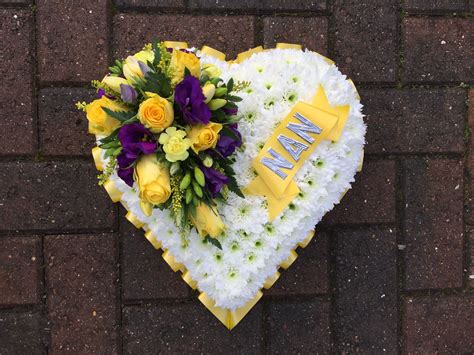 White Based Heart Flowers Funeral Tribute With Yellow And Purple Focal