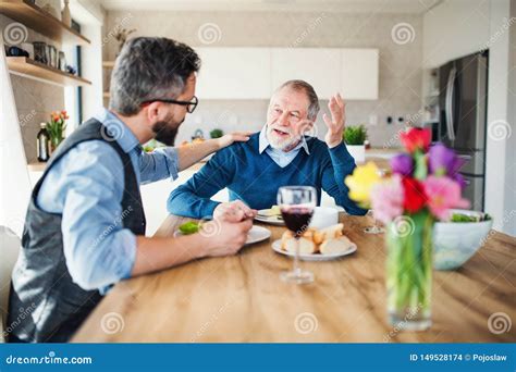 An Adult Hipster Son And Senior Father Indoors At Home Eating Light