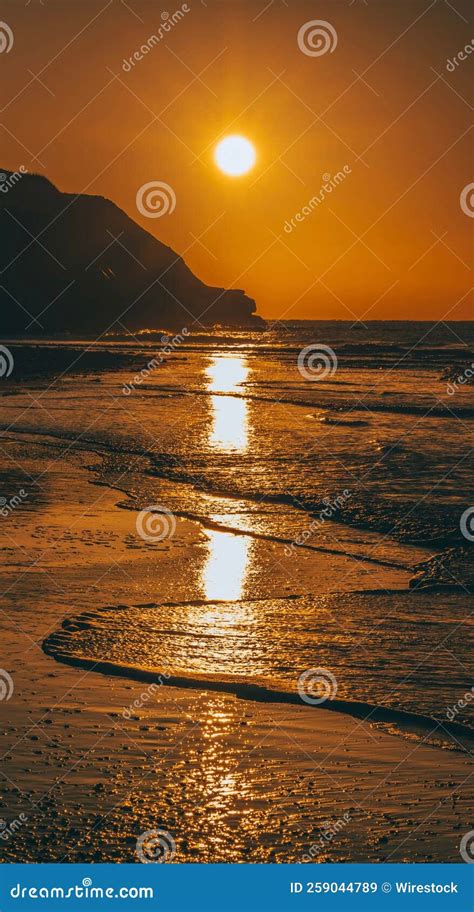 Vertical Shot Of Sunset Reflected On The Waves On The Beach Stock Image