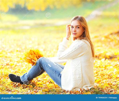 Beautiful Young Woman Sitting With Yellow Maple Leafs In Warm Sunny