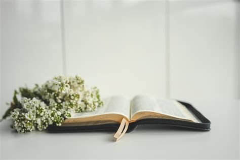 Biblia abierta con flores sobre un fondo blanco. | Foto Premium