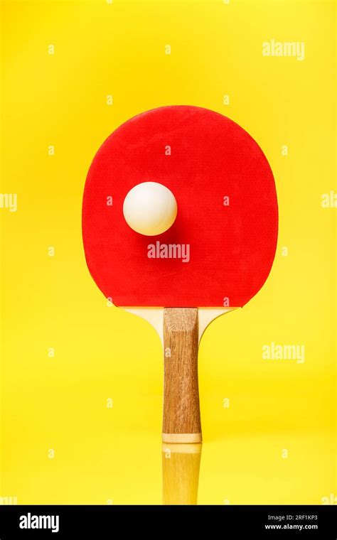 Red Side Of A Ping Pong Racket With A White Ball Standing On A Yellow