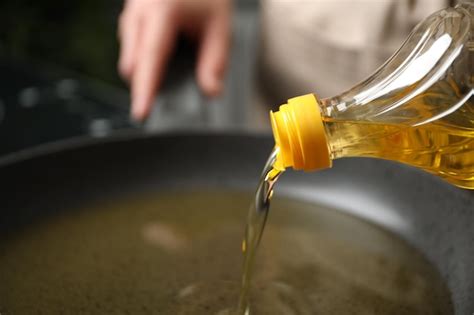 Premium Photo Woman Pouring Cooking Oil From Bottle Into Frying Pan