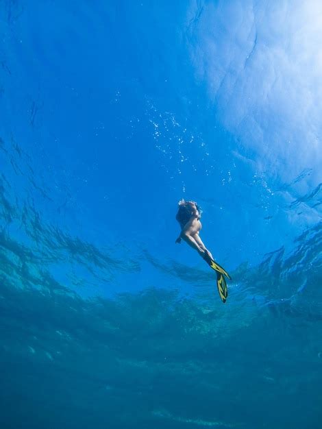 Hermosa mujer nadando bajo el agua con máscara de snorkel y aletas