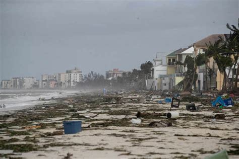 A Person Walks On Bonita Beach Amid Debris From The Storm Surge