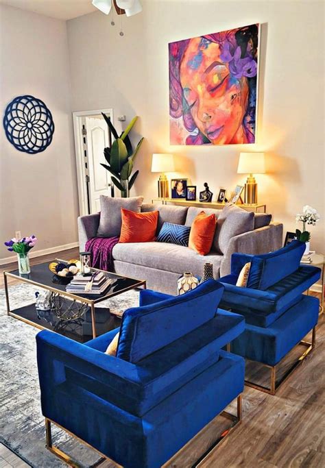 A Living Room Filled With Blue Couches Next To A Painting On The Wall