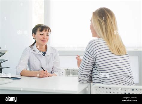 Friendly Female Doctor Comforting Middle Aged Patient In Hospital Stock