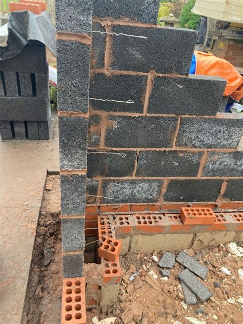 A Brick Wall Being Built With Bricks And Cement Blocks On The Ground