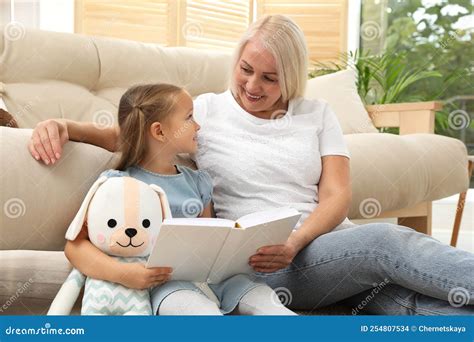 Happy Grandmother With Her Granddaughter Reading Book Together Stock