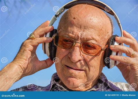 Portrait Of A Bald Elderly Man Listening To Music With Headphones