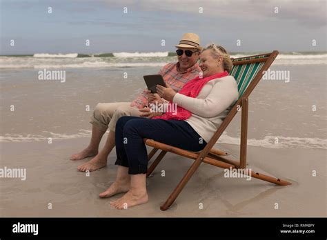 Senior Couple Using Digital Tablet While Relaxing In A Sun Lounger