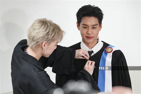 A Man Is Getting His Tie Put On By A Woman Who Is Wearing A Black Robe