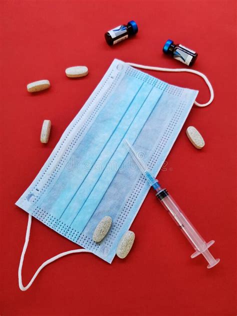 Medical Mask Tablets Syringes On A Uniform Red Background