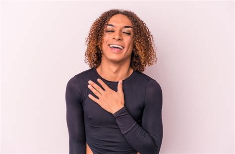 Joven mujer transexual latina aislada de fondo rosa se ríe a carcajadas manteniendo la mano en