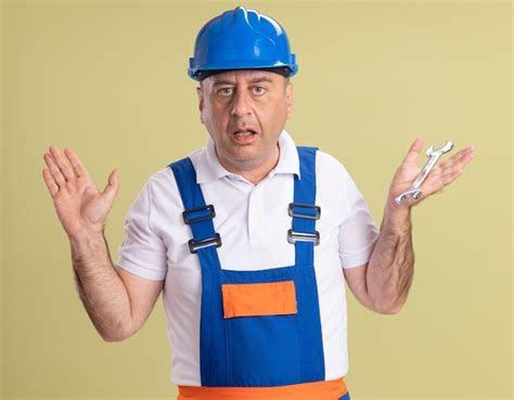 Free Photo Clueless Adult Builder Man In Uniform Stands With Raised