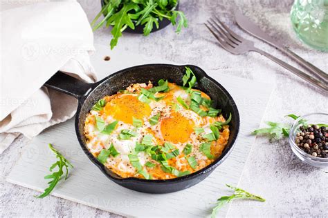 Shakshuka With Poached Eggs In Spicy Tomato Pepper Sauce And Arugula In