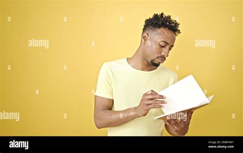 African American Man Reading Book Over Isolated Yellow Background Stock