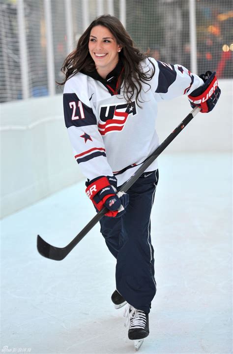 A Woman Is Playing Hockey On An Ice Rink And Smiling At The Camera With Her Stick