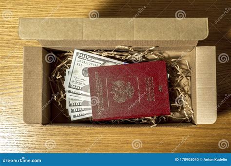 One Hundred Dollar Bills Enclosed In A Foreign Passport Lie In A