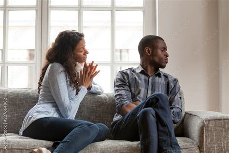 Black Couple In Love Sitting On Couch At Home Angry Dissatisfied