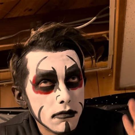 A Man With Black And White Face Paint On His Face Is Making A Hand Gesture