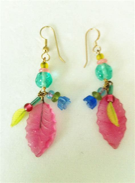 A Pair Of Earrings With Colorful Beads And Leaves On Them Sitting On A