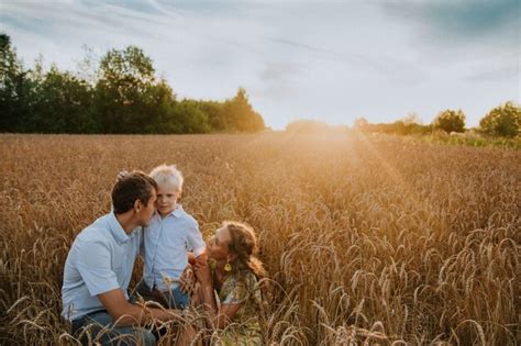 Uma família feliz caminha por um campo de trigo se divertindo e rindo