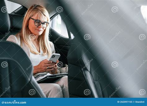 Sitting On The Backseat And Working Woman In White Formal Clothes Is