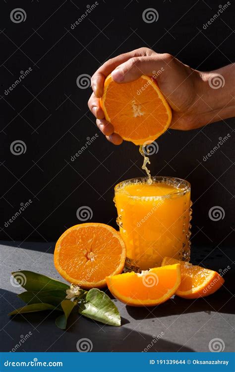 Mans Hand Sqeezing Orange Juice Into The Glass In The Bright Sunlite