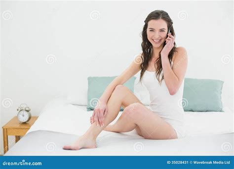 Jovem Mulher Relaxado Que Usa O Telefone Celular Na Cama Imagem De