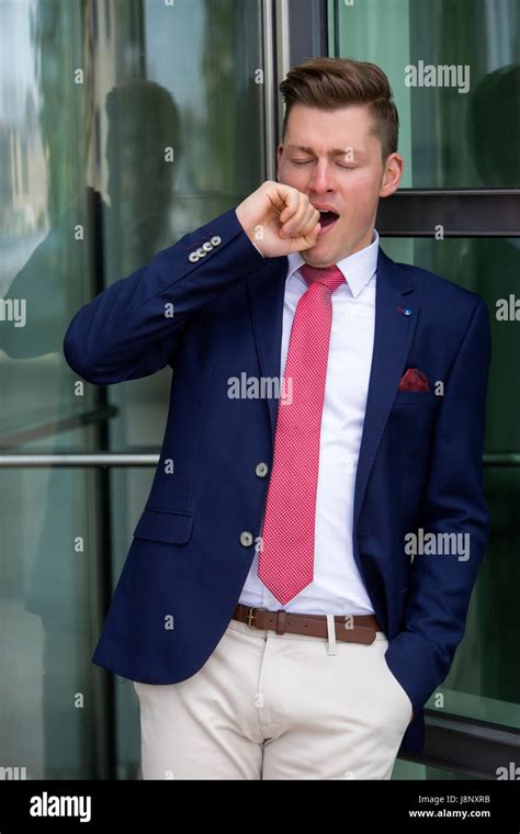 Handsome Blond Man In Suit Leaning Against Window And Yawning Stock