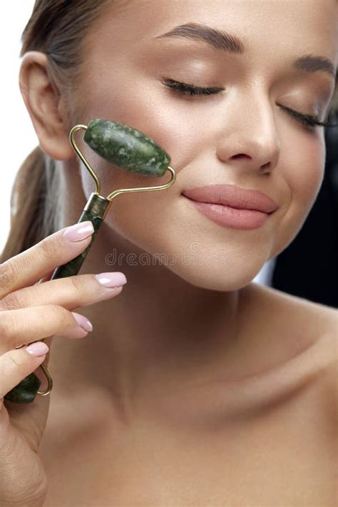 Portrait Of Happy Female Doing Face Massage With Jade Rollers For Spa