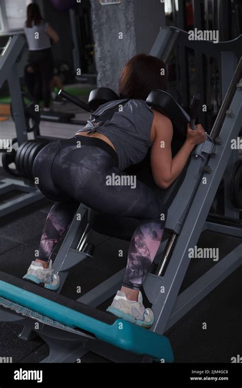 Vertical Rear View Shot Of A Female Bodybuilder Doing Squats In Hack