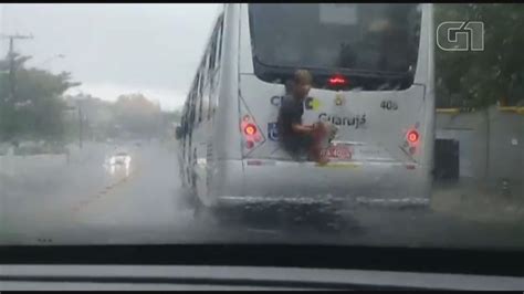 Homem se arrisca e pega carona na traseira de ônibus durante temporal