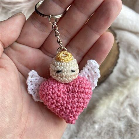 A Small Crocheted Angel Keychain Is Held In Someone S Hand