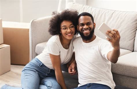 Black Couple Making Selfie Sitting Near Moving Boxes At Home Stock