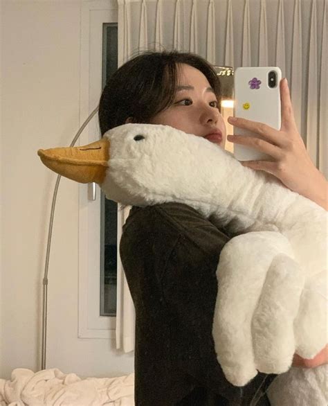 A Woman Taking A Selfie With Her Phone While Holding A Stuffed Duck In