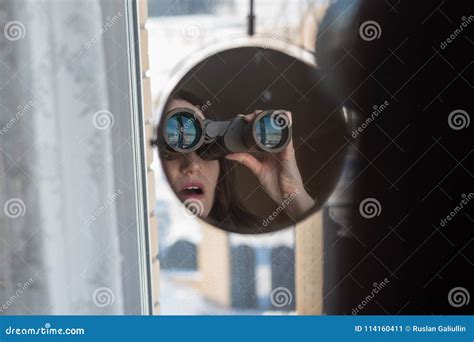 Portrait Of A Surprised Brunette With Binoculars Looking Out The Window Spying On Neighbors