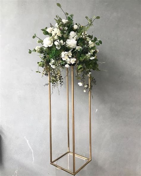 A Vase Filled With White Flowers Sitting On Top Of A Metal Stand