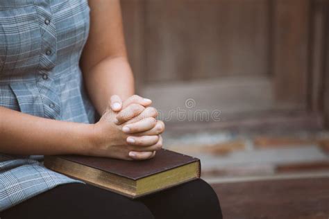 Hands Folded In Prayer On A Holy Bible In Church Concept For Faith