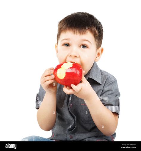 Close-up portrait of a little boy eating red apple isolated on white ...